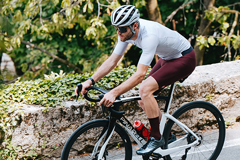 man-in-korte-zomer-fietsbroek-op-racefiets-afdalend-van-helling.jpg