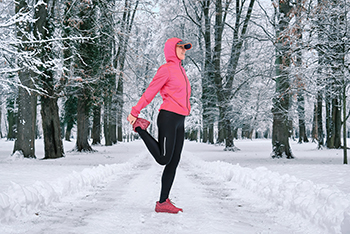 vrouw-hardlopen-strek-oefeningen-in-winterbos.jpg