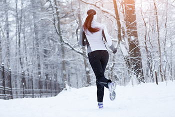 vrouw-hardlopend-in-besneeuwd-bos-tijdens-winter.jpg