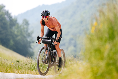 vrouw-heuvel-klimmend-op-racefiets-in-korte-fietsbroek-zonder-bretels-en-in-fietsshirt.jpg