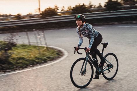 vrouw-op-racefiets-heuvel-klimmen-in-lange-winter-fietsbbroek-en-winter-fietsjas.jpg