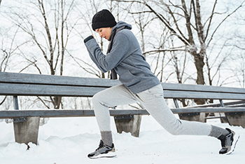 vrouw-strekoefeningen-bij-bankje-buiten-in-sneeuw.jpg